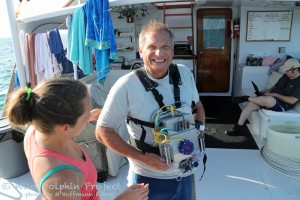 Dr. Adam Pack, an associate professor at the University of Hawaii at Hilo and long-time colleague of the Wild Dolphin Project, wears a CHAT box prior to entering the water. Georgia Tech team members Celeste Mason and Dr. Thad Starner check the device physically, and via computer, before the system goes in the water.